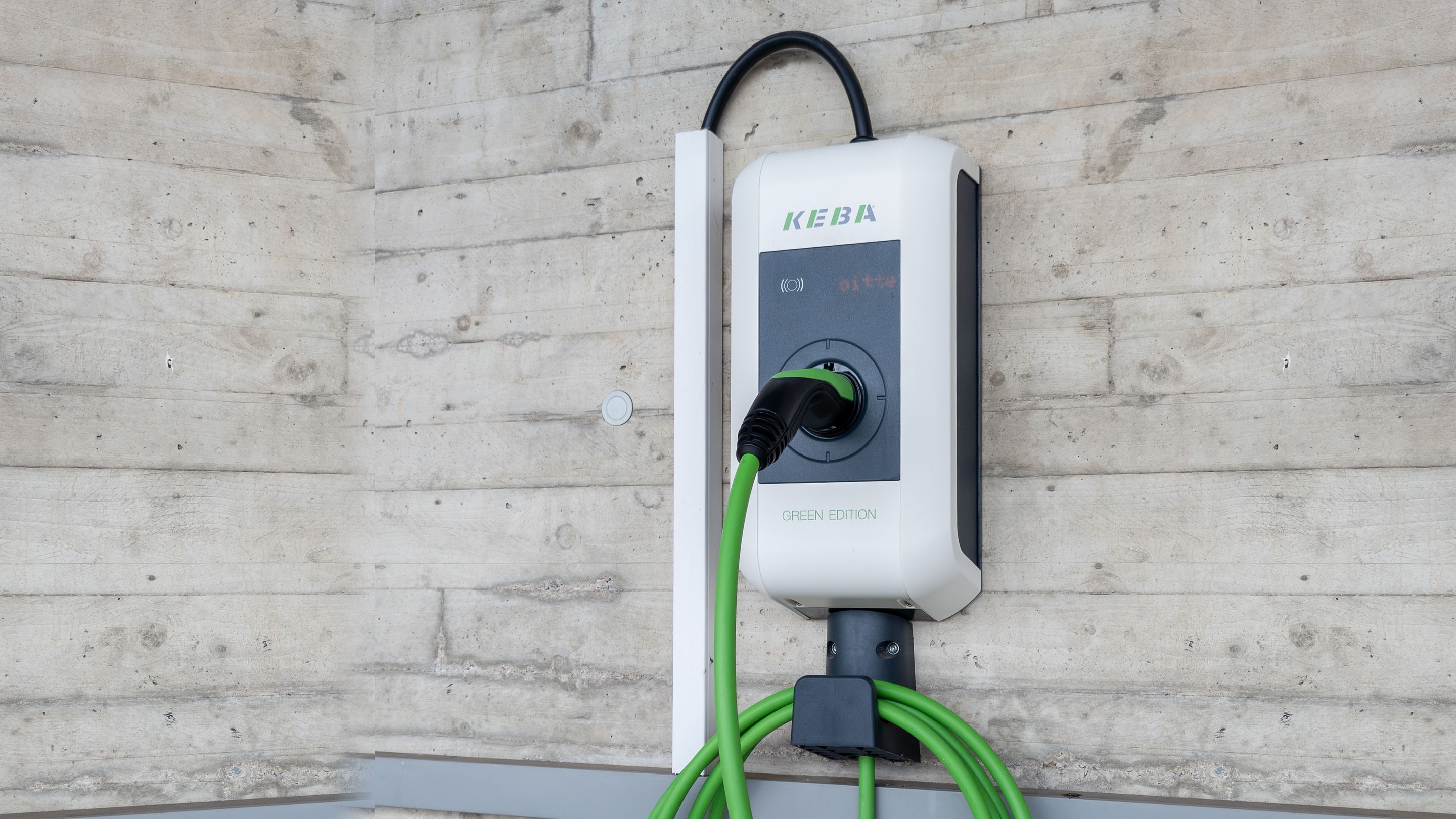 Wallbox mit angestecktem Ladekabel an einer Betonwand